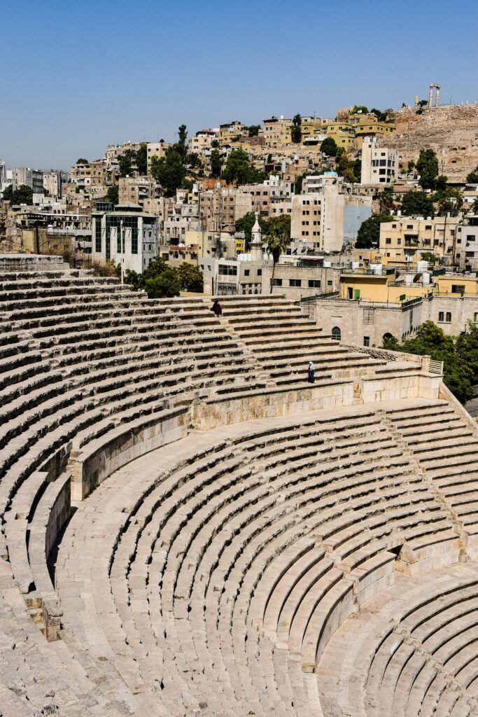 A view of the ancient Roman Amphitheater with modern Amman in the background, showcasing Jordanian history.